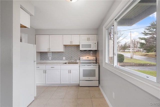 kitchen with white appliances, white cabinets, light countertops, and a sink