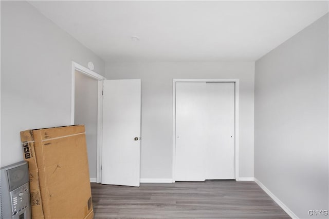 unfurnished bedroom with baseboards, wood finished floors, and a closet