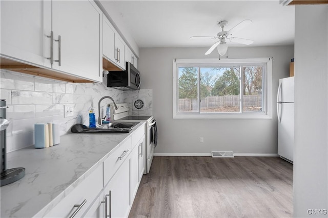 kitchen with decorative backsplash, visible vents, white appliances, a ceiling fan, and light stone counters