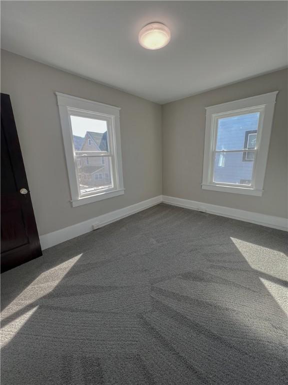 1230 Lake St, Elmira-City, NY 14901 - unfurnished room with baseboards, a wealth of natural light, and dark colored carpet