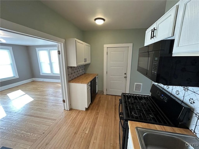 140 Riverside Dr, Utica, NY 13502 - kitchen with black microwave, stainless steel gas range, light wood-style flooring, and white cabinets