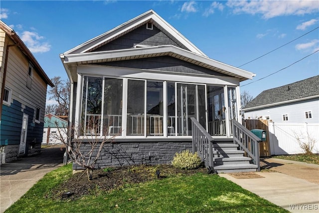 shotgun-style home featuring a sunroom and fence