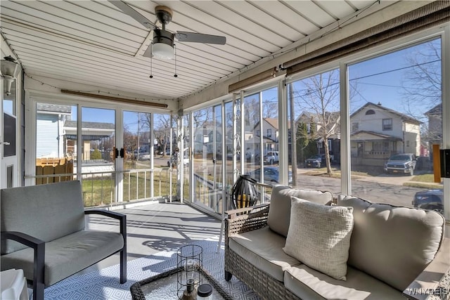 sunroom with a residential view, an outdoor living space, and a ceiling fan
