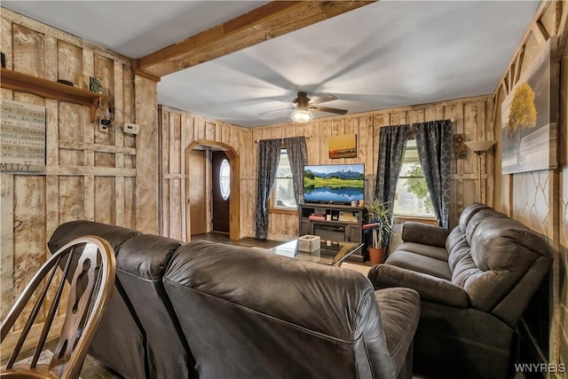 living area featuring wooden walls, arched walkways, and a ceiling fan