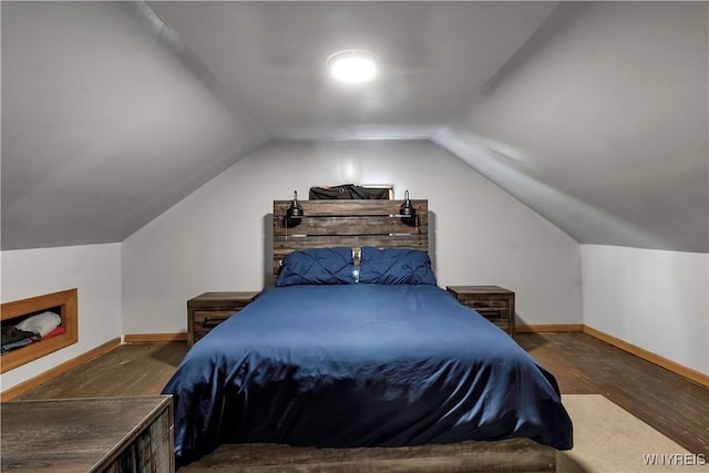 bedroom featuring baseboards, wood finished floors, and lofted ceiling