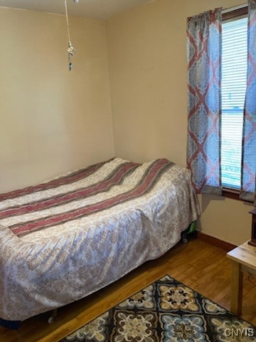 bedroom with baseboards, a ceiling fan, wood finished floors, and multiple windows