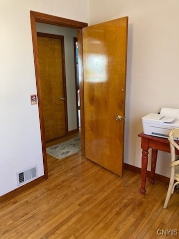 hall with light wood-type flooring, visible vents, and baseboards