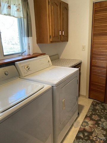 washroom featuring cabinet space and washer and clothes dryer