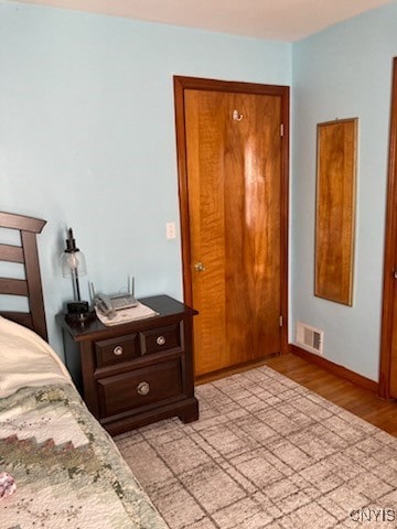 bedroom with visible vents, light wood finished floors, and baseboards