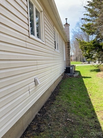 view of side of property featuring a lawn and cooling unit