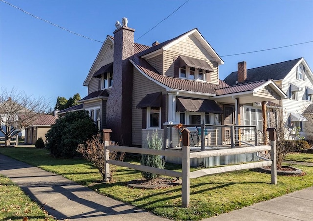 view of front of property featuring a front lawn, a chimney, a porch, and metal roof