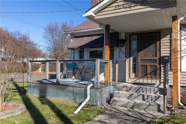 view of exterior entry featuring metal roof and a wooden deck