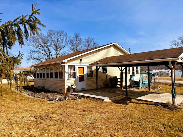 view of front facade with a sunroom, a front yard, and a shingled roof