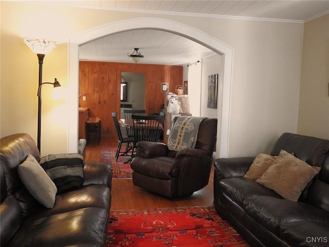 living room featuring arched walkways, crown molding, and wood finished floors