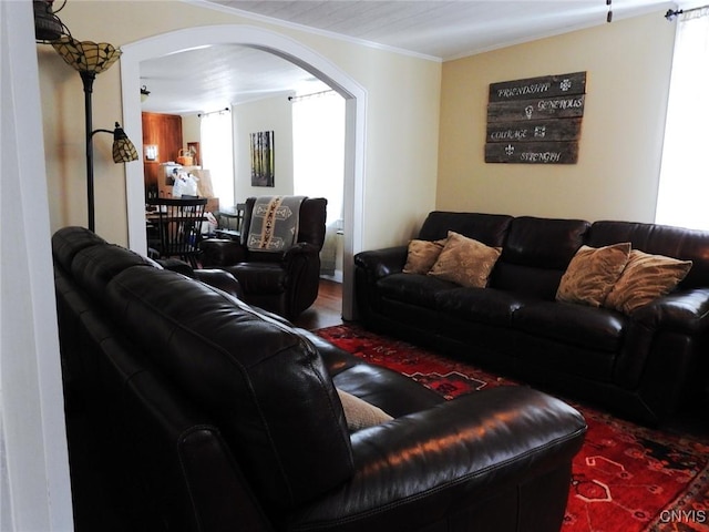 living room featuring arched walkways, crown molding, and wood finished floors