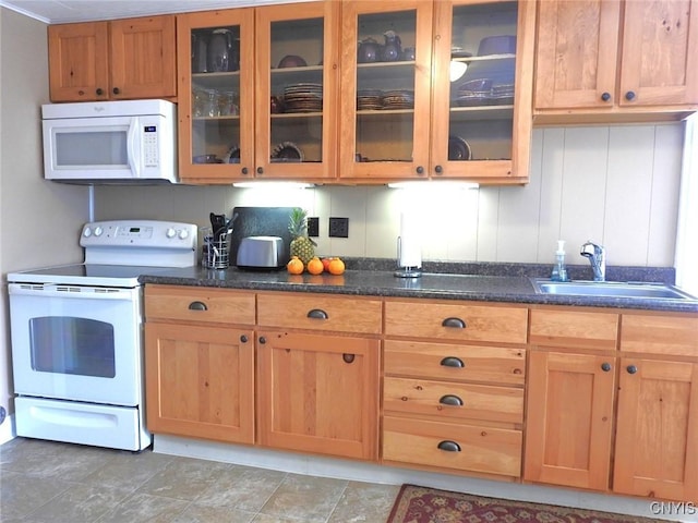 kitchen with white appliances, dark stone countertops, glass insert cabinets, and a sink