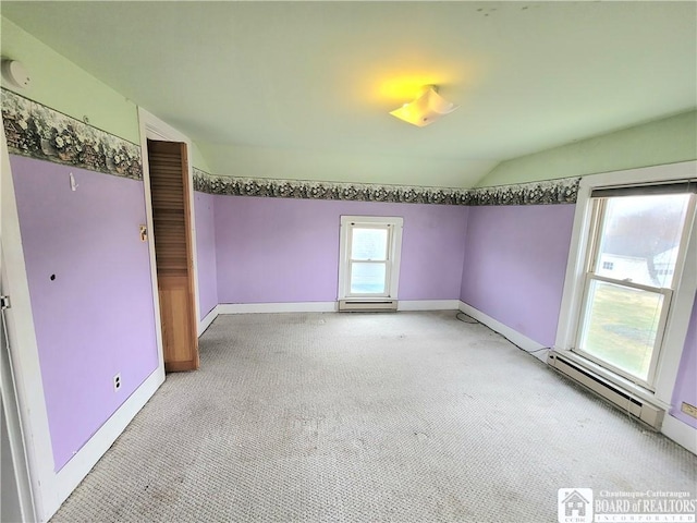 empty room featuring baseboards, lofted ceiling, baseboard heating, and light carpet