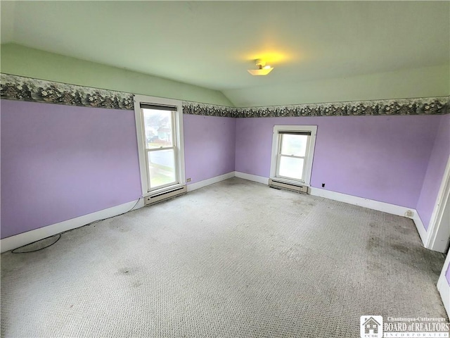 spare room with baseboards, lofted ceiling, light carpet, and a baseboard radiator