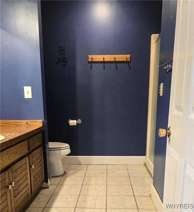 bathroom with baseboards, toilet, tile patterned flooring, and vanity