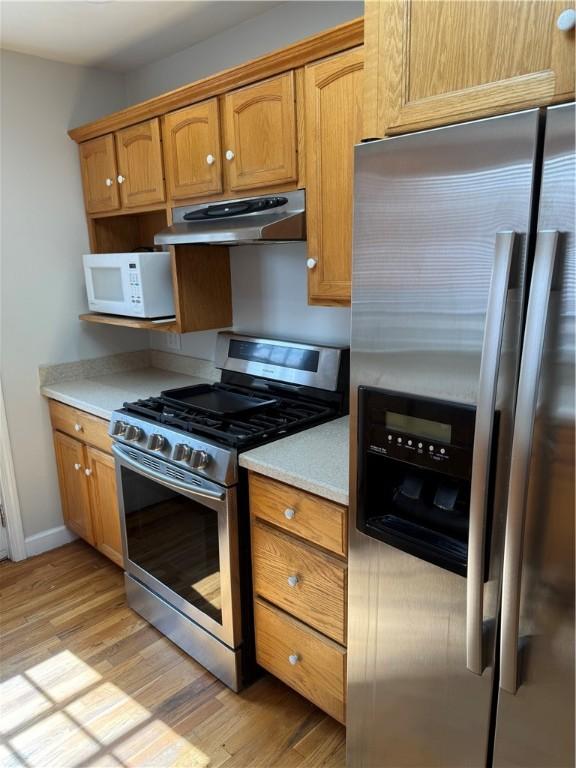 507 W Hudson St, Elmira-City, NY 14904 - kitchen with light countertops, brown cabinets, stainless steel appliances, under cabinet range hood, and light wood-type flooring