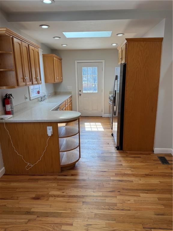 507 W Hudson St, Elmira-City, NY 14904 - kitchen with stainless steel refrigerator, light countertops, open shelves, a skylight, and light wood-style flooring