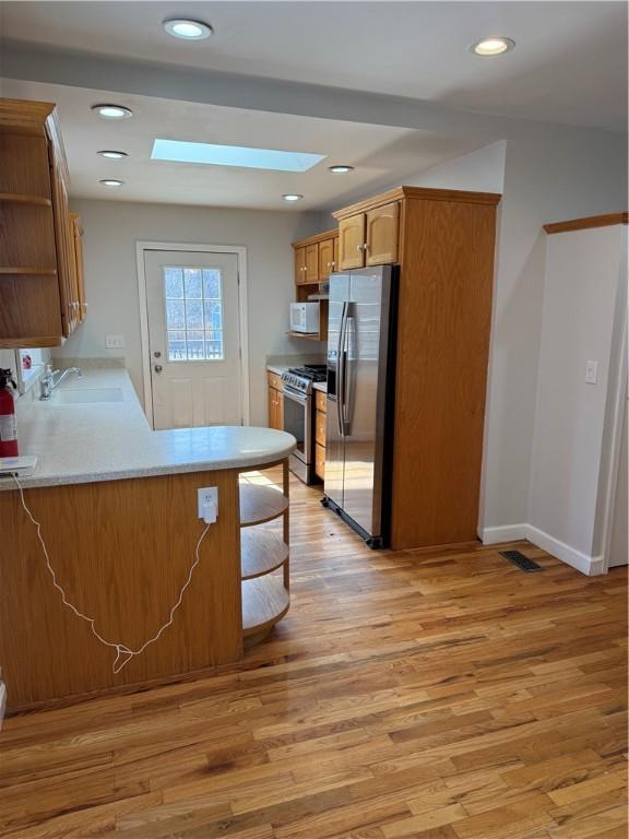 507 W Hudson St, Elmira-City, NY 14904 - kitchen featuring light wood-style flooring, a skylight, stainless steel appliances, a sink, and open shelves