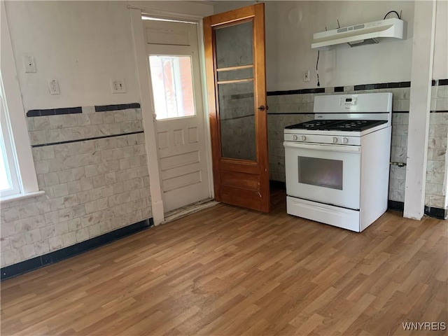 49 Newburgh Ave, Buffalo, NY 14211 - kitchen with white gas range, under cabinet range hood, tile walls, a wainscoted wall, and plenty of natural light