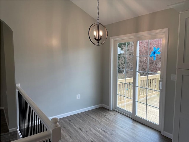 unfurnished dining area with baseboards, wood finished floors, vaulted ceiling, and plenty of natural light
