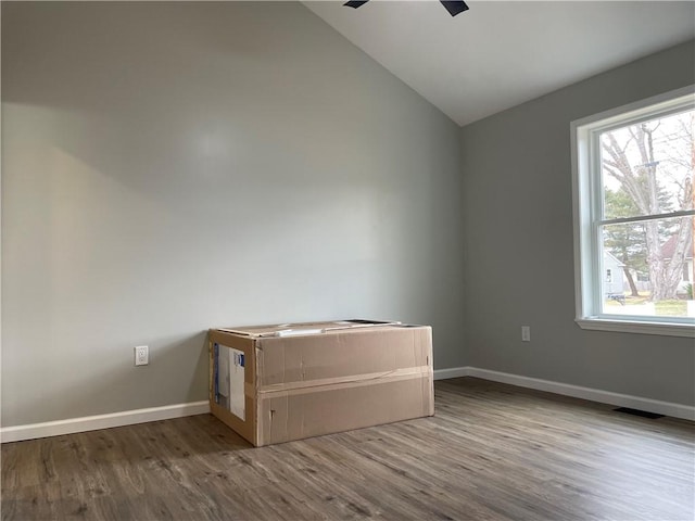 unfurnished room with visible vents, baseboards, wood finished floors, a ceiling fan, and vaulted ceiling