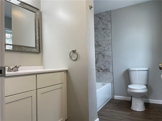 bathroom featuring baseboards, toilet, vanity, and wood finished floors