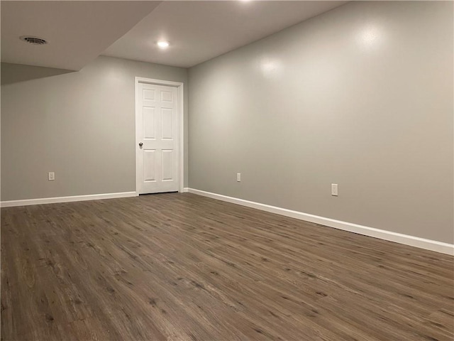 unfurnished room with baseboards, visible vents, and dark wood-style flooring