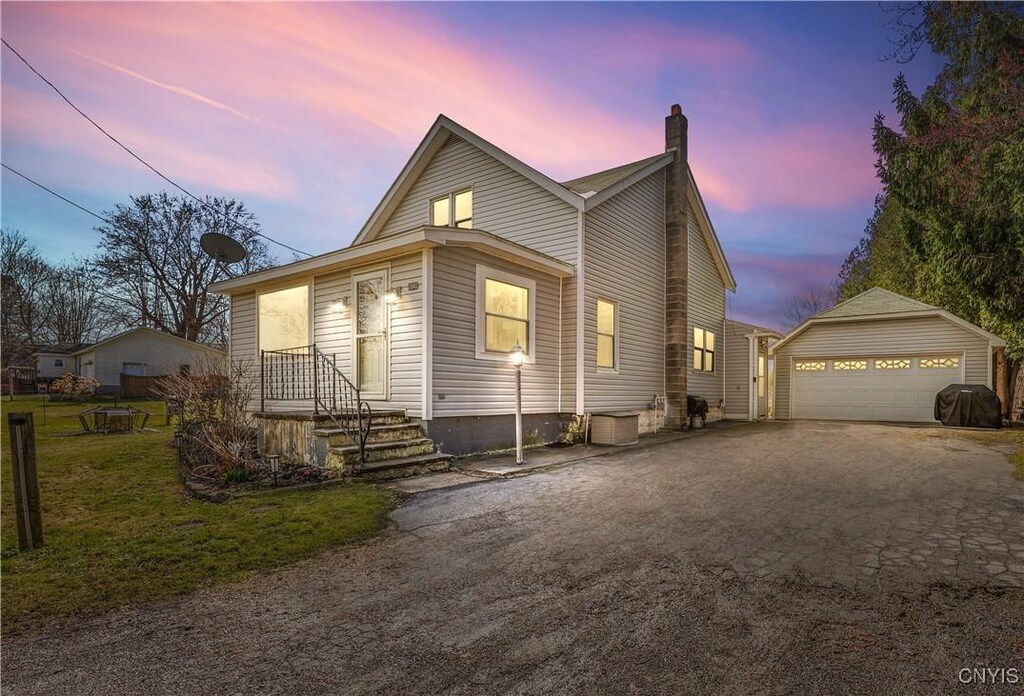 view of front of house featuring a detached garage, a lawn, an outbuilding, and a chimney