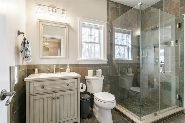 5027 Wyffels Rd, Canandaigua-Town, NY 14424 - bathroom featuring wainscoting, vanity, toilet, tile walls, and a stall shower