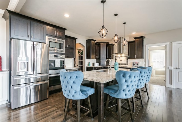 5027 Wyffels Rd, Canandaigua-Town, NY 14424 - kitchen with a sink, dark brown cabinetry, wall chimney range hood, arched walkways, and stainless steel appliances