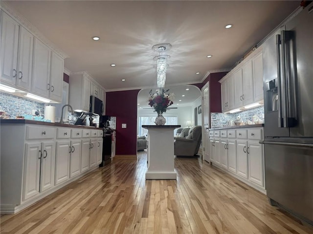 612 Oswegatchie Rd, Palatine, NY 13428 - kitchen featuring high end fridge, white cabinets, open floor plan, light wood finished floors, and crown molding