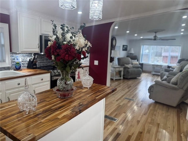 612 Oswegatchie Rd, Palatine, NY 13428 - kitchen featuring wood counters, open floor plan, white cabinets, crown molding, and recessed lighting