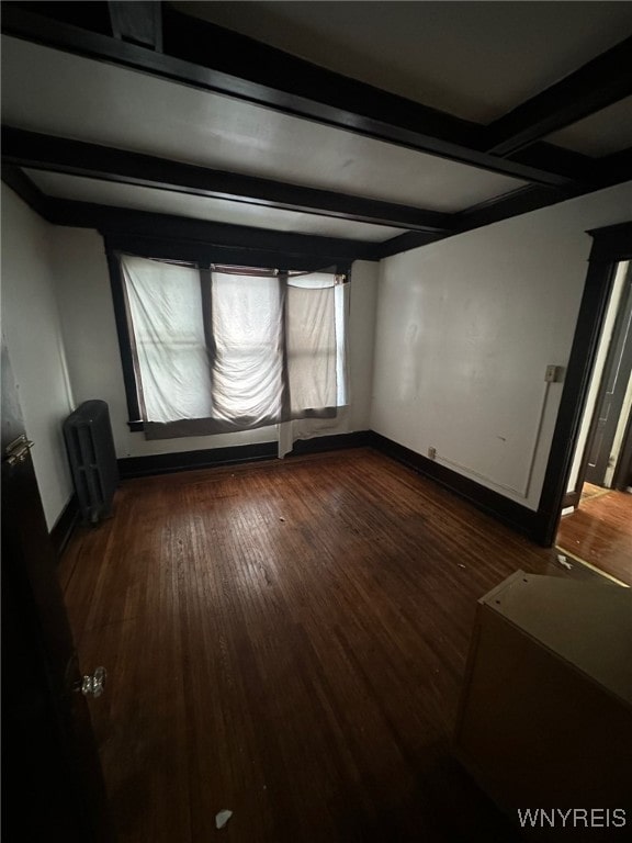 spare room featuring beamed ceiling, dark wood-type flooring, radiator heating unit, and baseboards