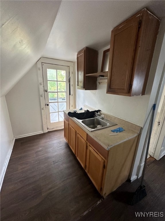 kitchen with lofted ceiling, dark wood-style floors, open shelves, a sink, and baseboards