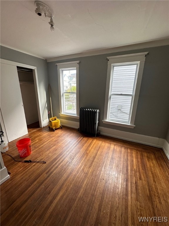 spare room featuring radiator, crown molding, and hardwood / wood-style flooring