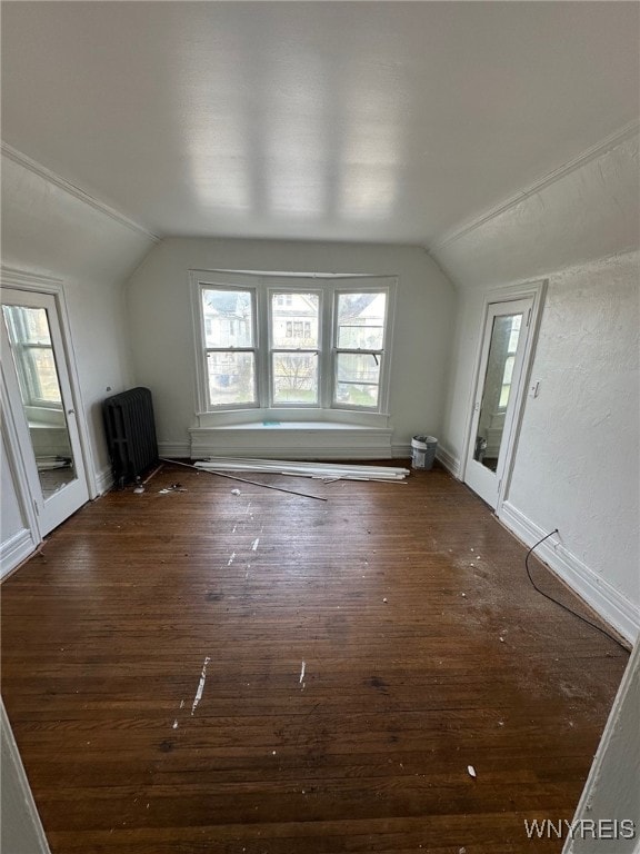 additional living space with radiator, vaulted ceiling, baseboards, and dark wood-style floors