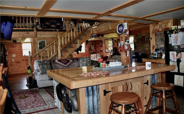 interior space with wood walls, a breakfast bar, and freestanding refrigerator