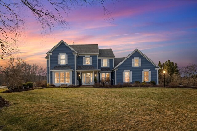traditional-style house with a front lawn and roof with shingles