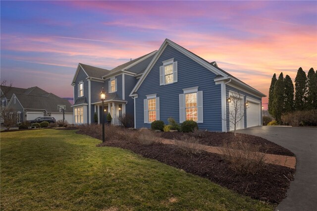traditional home featuring driveway, a front yard, and an attached garage
