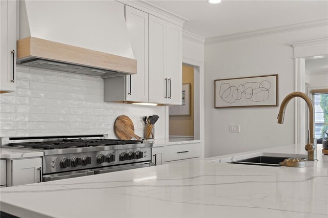 kitchen featuring custom exhaust hood, a sink, white cabinetry, high end stainless steel range oven, and crown molding