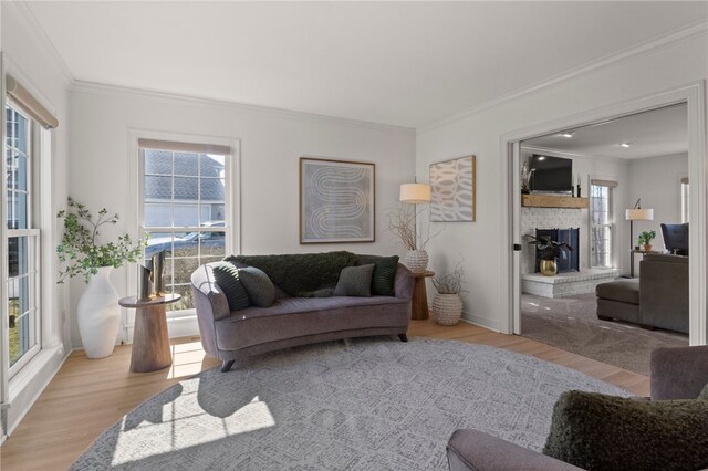 living area featuring wood finished floors, crown molding, baseboards, and a brick fireplace