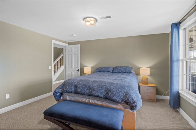 carpeted bedroom with visible vents, baseboards, and multiple windows