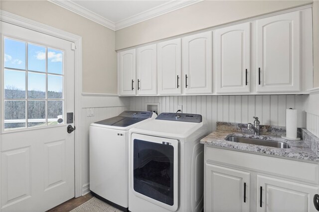 washroom featuring ornamental molding, a sink, cabinet space, and washer and clothes dryer