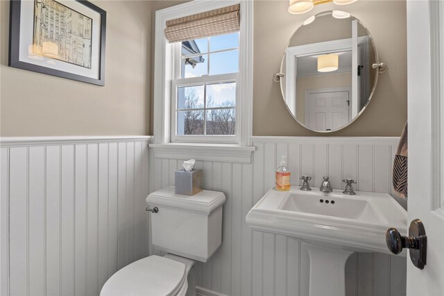 half bath featuring toilet and a wainscoted wall