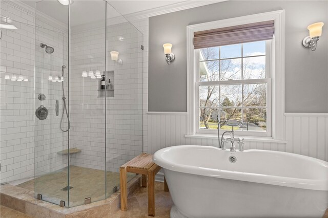 full bathroom featuring a shower stall, a wainscoted wall, and a soaking tub