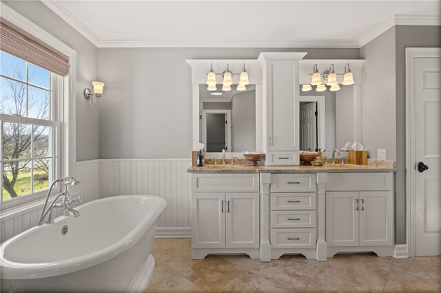 bathroom featuring a wainscoted wall, a sink, and a healthy amount of sunlight
